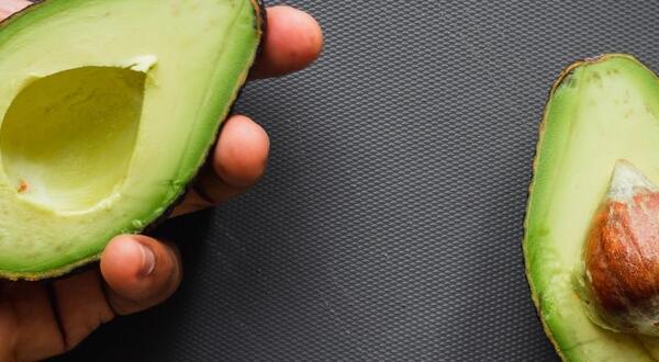 hand holding avocado half (c) Louis Hansel